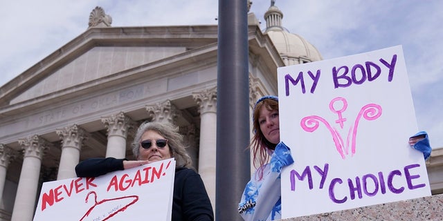 Dani Thayer, a la izquierda, y Marina Lanae, a la derecha, ambas de Tulsa, Oklahoma, sostienen carteles a favor del aborto en el Capitolio estatal, el 13 de abril en la ciudad de Oklahoma.  La Legislatura estatal de Oklahoma, liderada por los republicanos, aprobó varias restricciones contra el aborto en las últimas semanas, como parte de un movimiento en los estados conservadores para restringir los derechos reproductivos de las mujeres. 