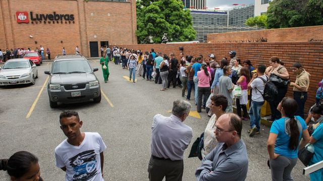 Venezolanos haciendo una larga fila para entrar a un supermercado.