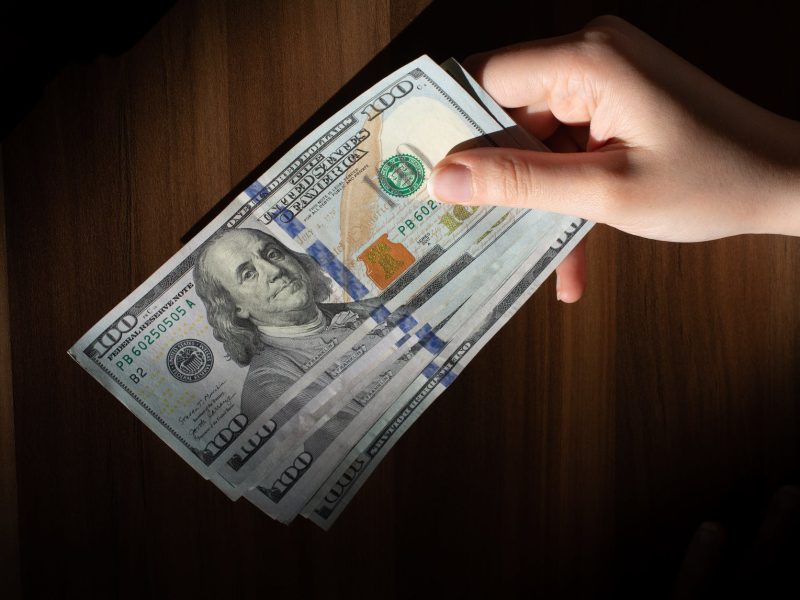 a person holding a stack of money on a table