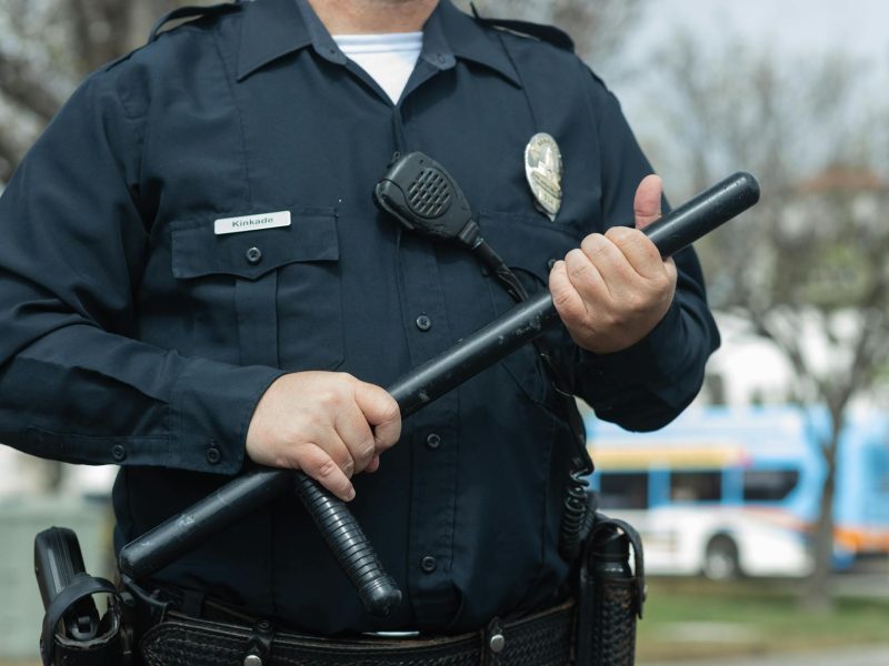 man in black police uniform holding a baton