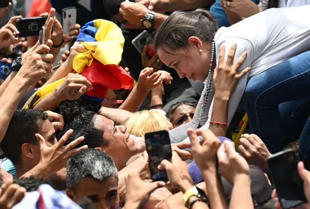 La líder opositora venezolana María Corina Machado saluda a simpatizantes durante un acto de campaña