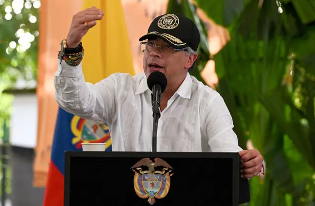 El presidente de Colombia, Gustavo Petro, pronuncia un discurso. Va vestido con camisa blanca y gorra negra. Está apoyado sobre un atril y detrás de él hay una bandera de Colombia. 