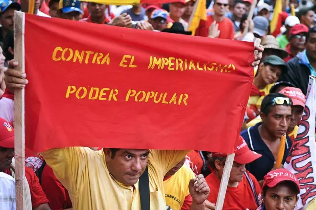 Un hombre carga una pancarta roja con un mensaje que dice: 